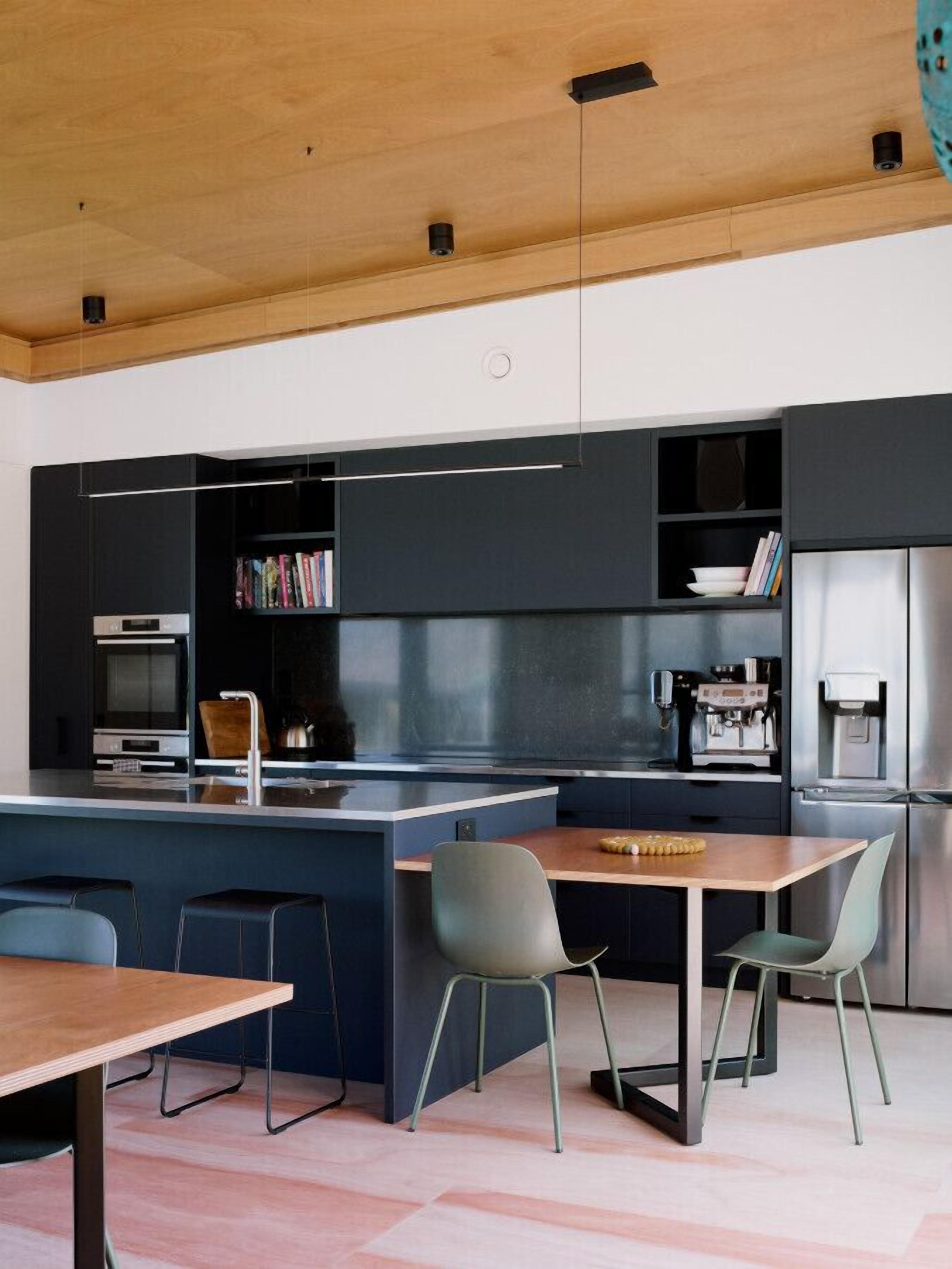 A modern kitchen with a central island, bar stools, and built-in appliances.