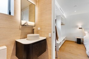 A modern bathroom with a round sink, a mirror, and a towel hanging on the wall.