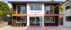 Ein zweistöckiges Gebäude mit Balkonen, einer Beschilderung mit der Aufschrift 'ALP STUDIOS' und einem Hinweisschild für reservierte Zimmer.
