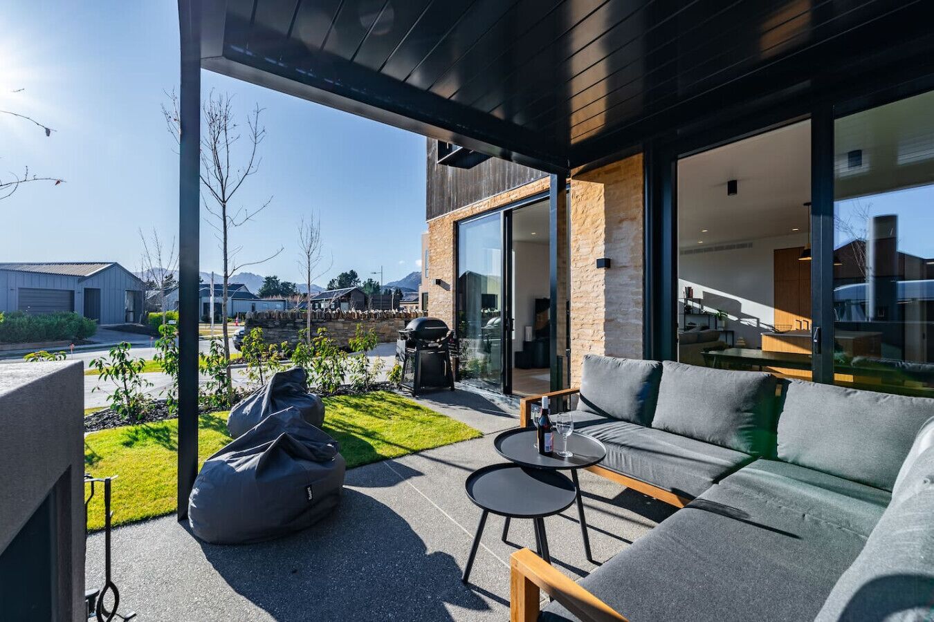 A modern outdoor living area with a sofa, a small table, and a grill.