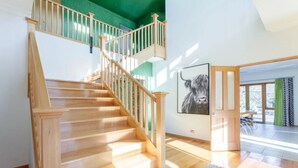 Una scala in legno con vista su una sala da pranzo e un'ampia opera d'arte a tema toro.
