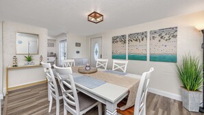 A dining area with a white table, chairs, and a ceiling light fixture. - Charming 3BR retreat w/ Private yard- 15 min to Gulf Beaches & 6 min to DTSP (St. Petersburg)