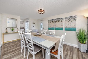A dining area with a white table, chairs, and a ceiling light fixture. - Charming 3BR retreat w/ Private yard- 15 min to Gulf Beaches & 6 min to DTSP (St. Petersburg)