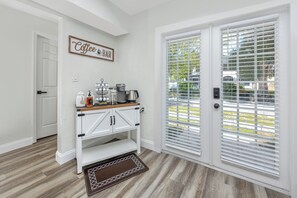 A kitchen with a coffee bar, white cabinetry, and a view through the door. - Charming 3BR retreat w/ Private yard- 15 min to Gulf Beaches & 6 min to DTSP (St. Petersburg)