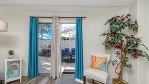 A room with a white sofa, teal curtains, a potted plant, and a view of the outside. - Charming 3BR retreat w/ Private yard- 15 min to Gulf Beaches & 6 min to DTSP (St. Petersburg)