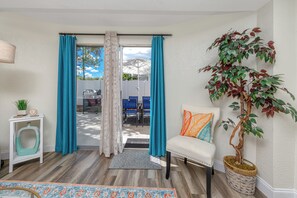 A room with a white sofa, teal curtains, a potted plant, and a view of the outside. - Charming 3BR retreat w/ Private yard- 15 min to Gulf Beaches & 6 min to DTSP (St. Petersburg)