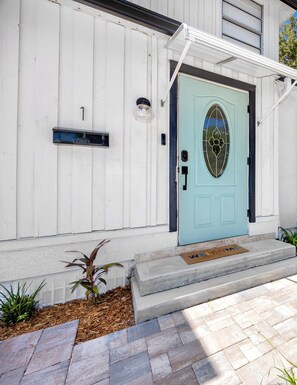 A house with a light blue door, a mailbox, and a welcome mat. - Charming 3BR retreat w/ Private yard- 15 min to Gulf Beaches & 6 min to DTSP (St. Petersburg)