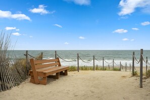 A wooden bench on a sandy beach with a wooden fence and rope barrier, overlooking the ocean. - Ocean View Getaway - Pool & Grill (Frankford)
