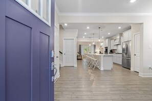 A modern kitchen with white cabinetry, stainless steel appliances, and a central island with bar stools. - Ocean View Getaway - Pool & Grill (Frankford)