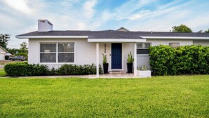 A single-story house with a dark blue door, white siding, and a grey roof. - 10 min to Beach, Peloton, Game Room, King Bed (Bradenton)
