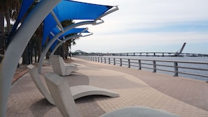 A waterfront promenade with modern seating and a view of the sea. - 10 min to Beach, Peloton, Game Room, King Bed (Bradenton)