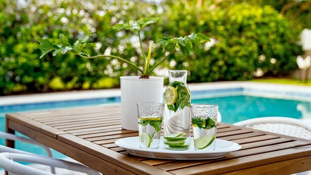 A wooden table with a tray holding two glasses of a beverage with lime slices and mint leaves, a pitcher, and a potted plant. - 10 min to Beach, Peloton, Game Room, King Bed (Bradenton)
