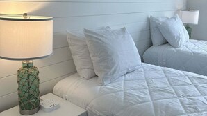 A bedroom with two beds, a nightstand with a lamp, a wall-mounted painting, and a wooden headboard. - Callaway Corner | Luxe Pet-Friendly 2BR Condo (Myrtle Beach)