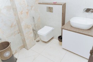 A bathroom with a white toilet, a sink, and a shower. - HOTEL STAR DELIGHT (Prayagraj)