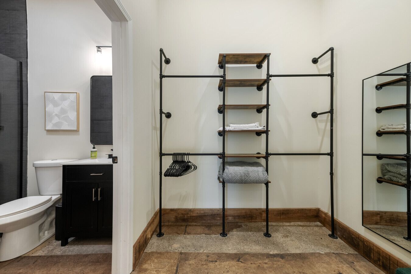 Et badeværelse med toilet, vask, håndklædetørrestativ og spejl.