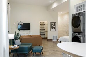 A modern living room with a sofa, ottoman, and a flat-screen TV. - Modern Loft-Style Retreat Near Blenko Glass – Milton, WV (Milton)