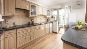 Een moderne keuken met lichte houten kastjes, een granieten aanrechtblad en een ingebouwde vaatwasser.