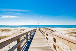 A wooden boardwalk leading to a beach with clear skies.