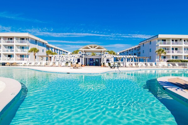 A hotel with a large swimming pool, multiple balconies, and a covered entrance.