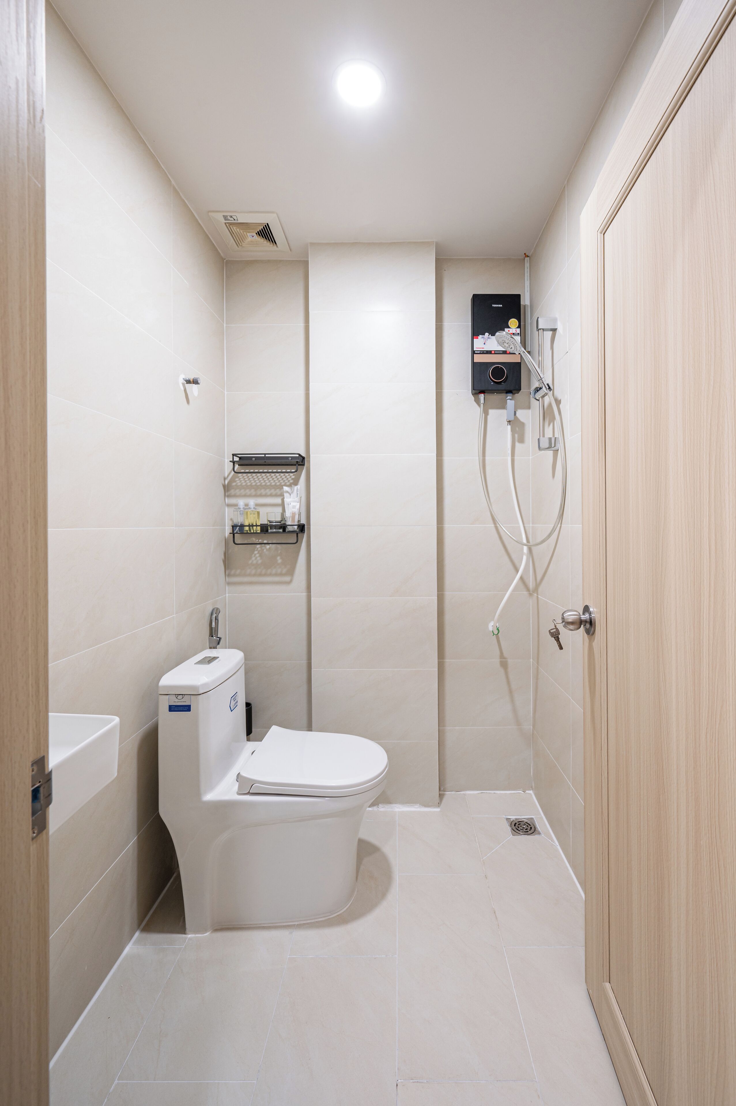 A compact bathroom with a toilet, a shower unit, and a sink.