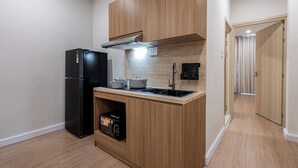 Eine kleine Küche mit Holzausstattung, einem schwarzen Kühlschrank, einer Mikrowelle und einem Herd.