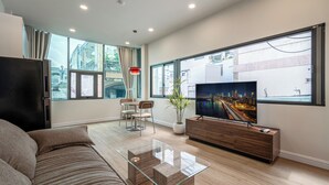 Un salon moderne avec un canapé, une table basse en verre, un téléviseur et une vue sur la ville.
