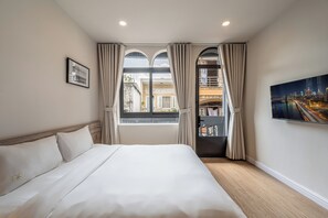 A hotel room with a large bed, a cityscape view through the window, and a painting on the wall. - Home by CR Concept in The Center (Ho Chi Minh City)