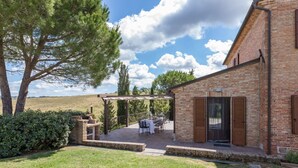 Una casa de ladrillo con patio, mobiliario exterior y una pérgola.