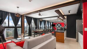 A modern apartment with a dining area, kitchen, and a large window offering a city view.