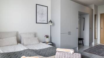 A modern bedroom with a bed, grey wardrobe, and a framed map on the wall.