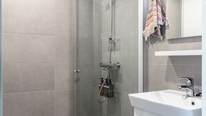 A modern bathroom with a glass shower enclosure, a white sink, and a mirror above it. - Modern Studios next to Railway Station (Lahti)