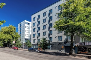A modern multi-story building with a flat facade, large windows, and balconies.