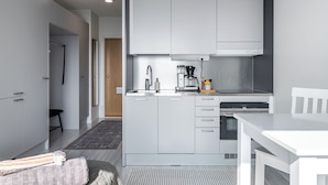 A modern kitchen with white cabinetry, a built-in oven, and a coffee maker. - Modern Studios next to Railway Station (Lahti)