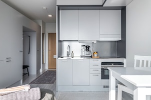 A modern kitchen with white cabinetry, a built-in oven, and a coffee maker.
