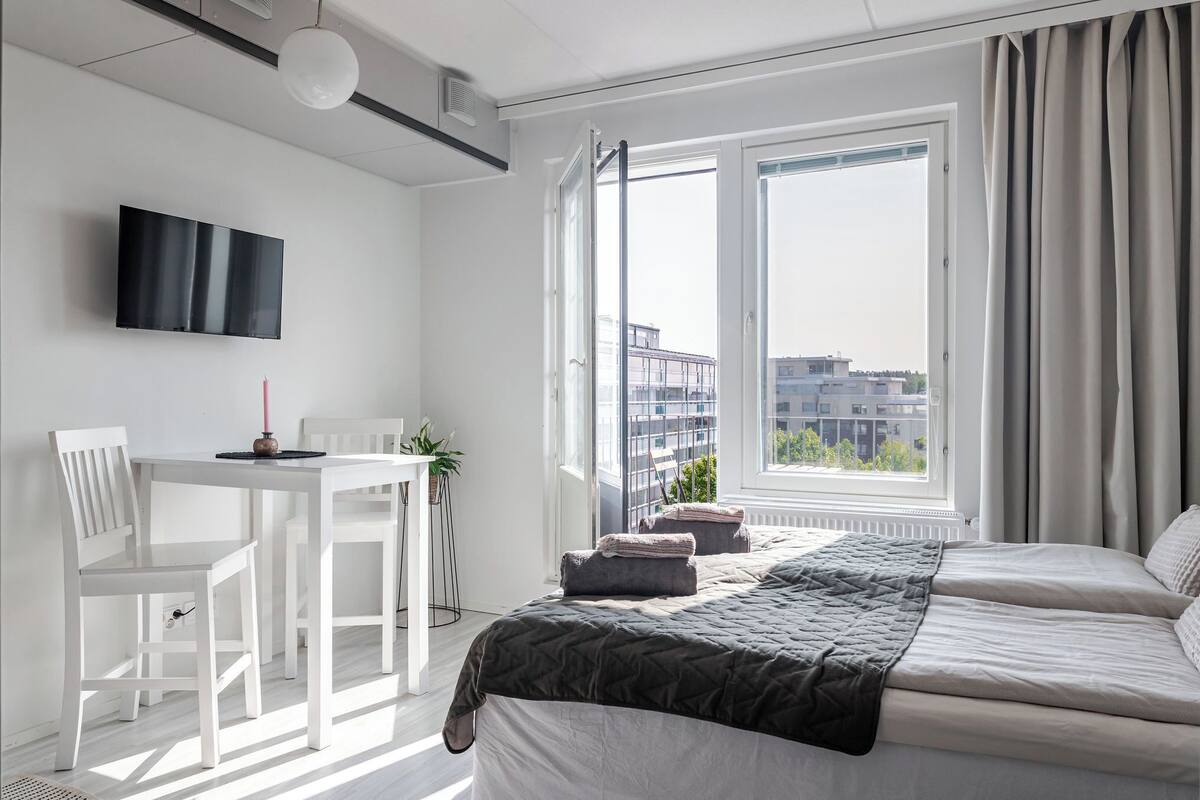 A modern hotel room with a bed, a desk, and a TV.