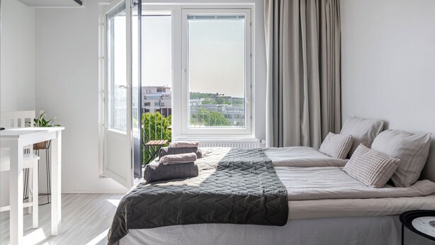 A bedroom with a bed, a desk, and a window with curtains. - Modern Studios next to Railway Station (Lahti)