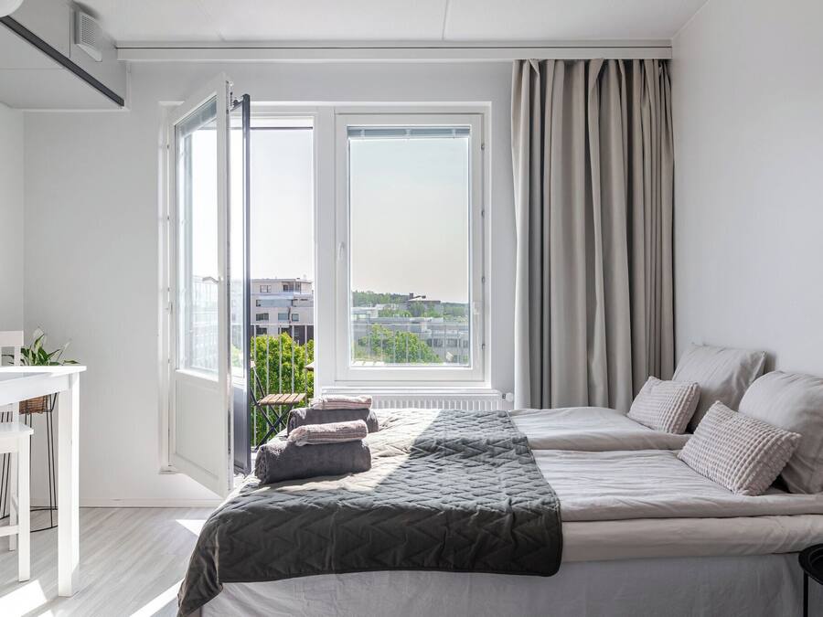 Un dormitorio con cama, escritorio y ventana con cortinas.