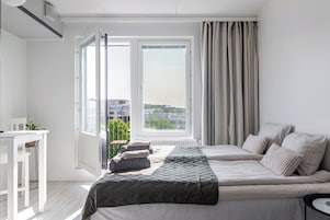 A bedroom with a bed, a desk, and a window with curtains.
