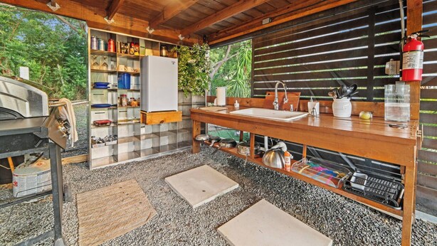 A rustic kitchen with a wooden countertop, a sink, and a fire extinguisher.