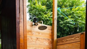 A wooden shower enclosure with a metal faucet and a small window.