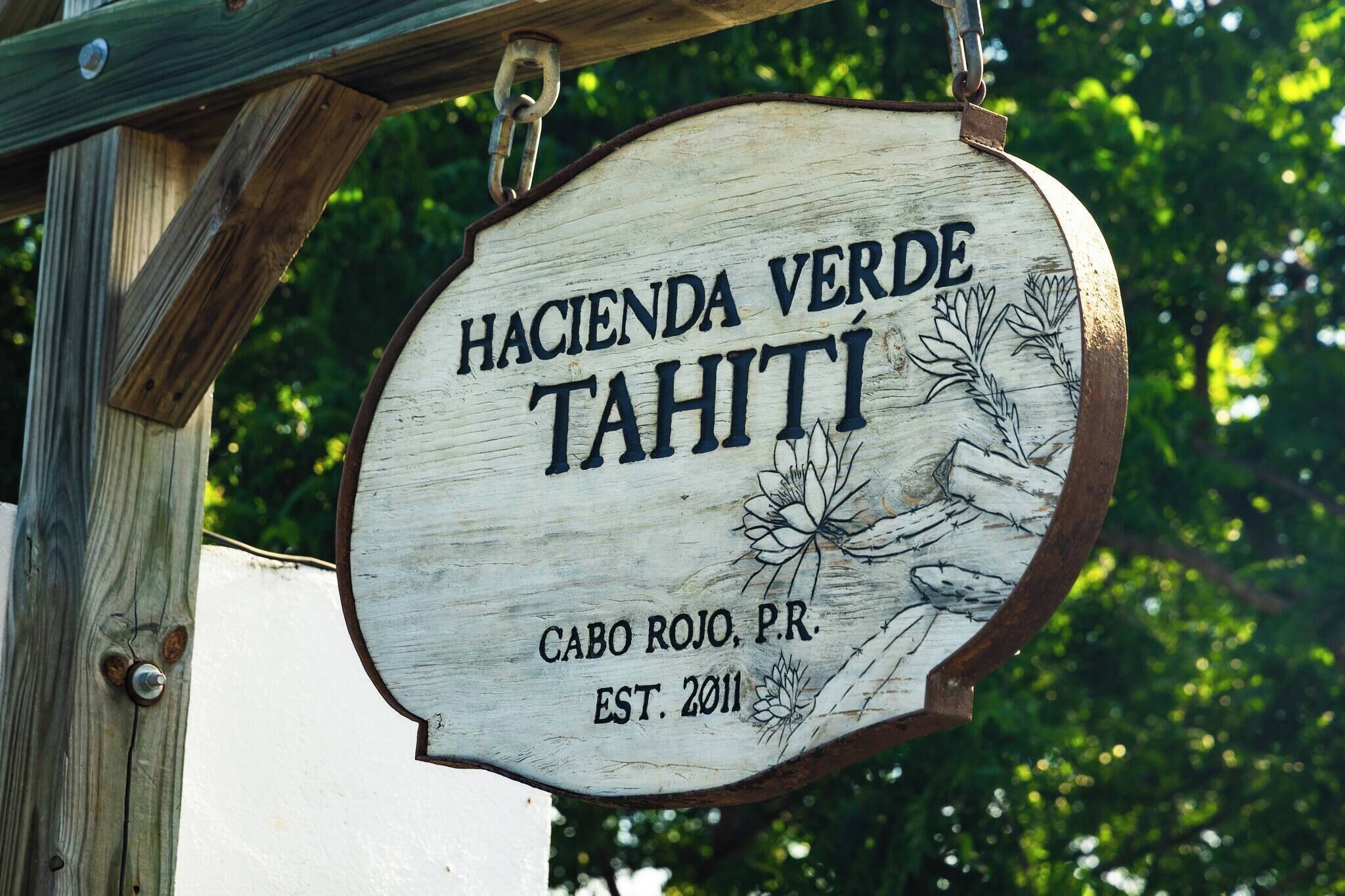 A wooden sign with the text "Hacienda Verde Tahiti" and "Cabo Rojo, P.R. EST. 2011".