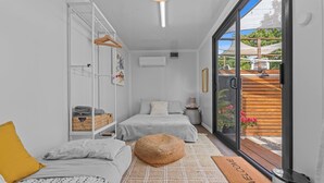 Un dormitorio moderno y bien iluminado con un amplio ventanal corredera que da a un espacio exterior.