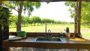 Una cabaña de madera rústica con una mesa de madera, un lavabo y vistas a un viñedo.