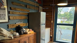 Eine Küche mit Holzausstattung, einem Kühlschrank, einer Kaffeemaschine und einem Fenster mit Blick ins Freie.