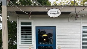Ein weißes Gebäude mit einer blauen Tür und einem Schild, auf dem "LA CABANA DE LOS CABALLOS" steht.