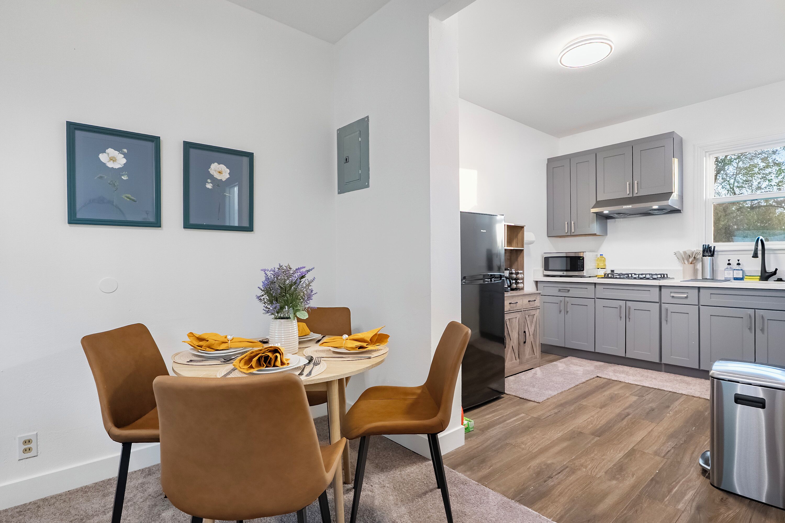A modern kitchen with grey cabinets, a stainless steel refrigerator, and a microwave.