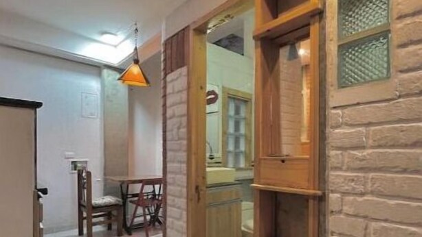 Un couloir avec une porte en bois, un sol carrelé et, au fond, un coin repas.