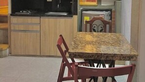 Une cuisine compacte avec un coin repas, comprenant une table et des chaises, un luminaire suspendu et un réfrigérateur.