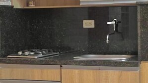 Une cuisine avec des meubles en bois, un plan de travail en granit, un évier en acier inoxydable et une cuisinière à gaz.