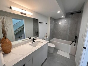 A modern bathroom with a large mirror, a double sink, a toilet, and a bathtub. - Lakeside Gem - Frenchman's Bay (Pickering)